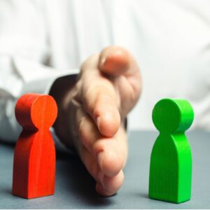 Image showing a red and green wooden 'person' on a table with a real persons hand on a table separating them