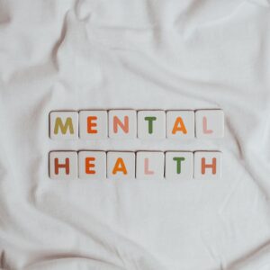 Letter tiles spelling out Mental health on a white ruffled sheet