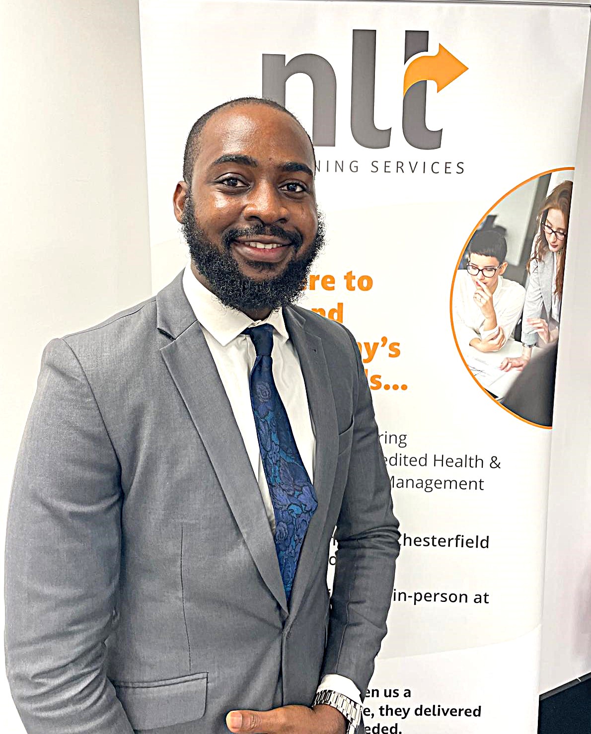 Peter Aderoju, standing in front of NLT roller banner