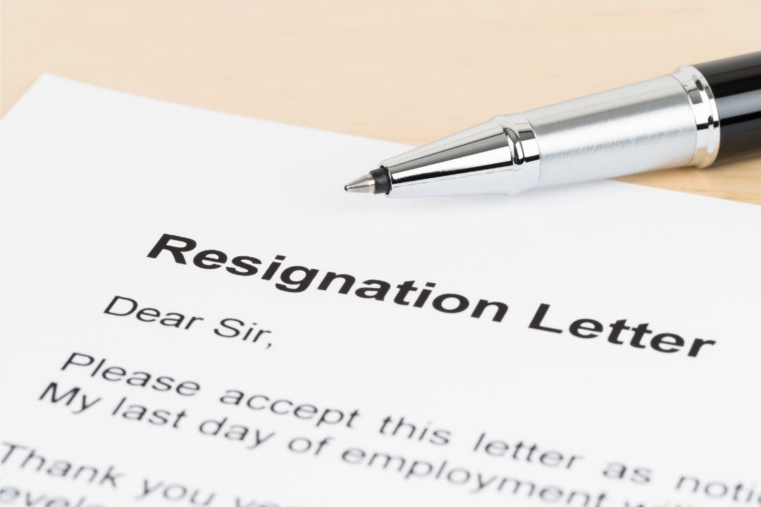 Close-up of the a letter showing the top corner titled 'Resignation Letter' and continues Dear Sir....with a pen on top of it