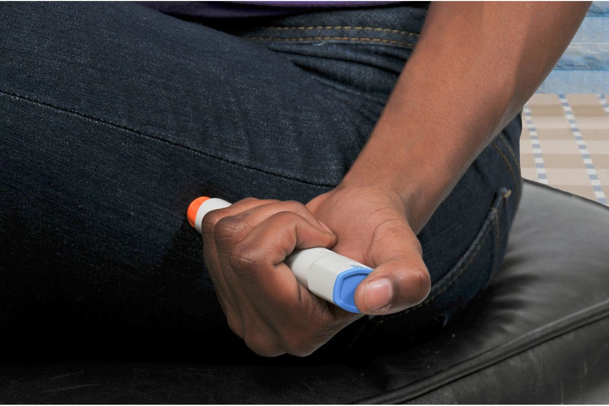 image showing epipen appearing to be held and about to be injected into a leg through their jeans