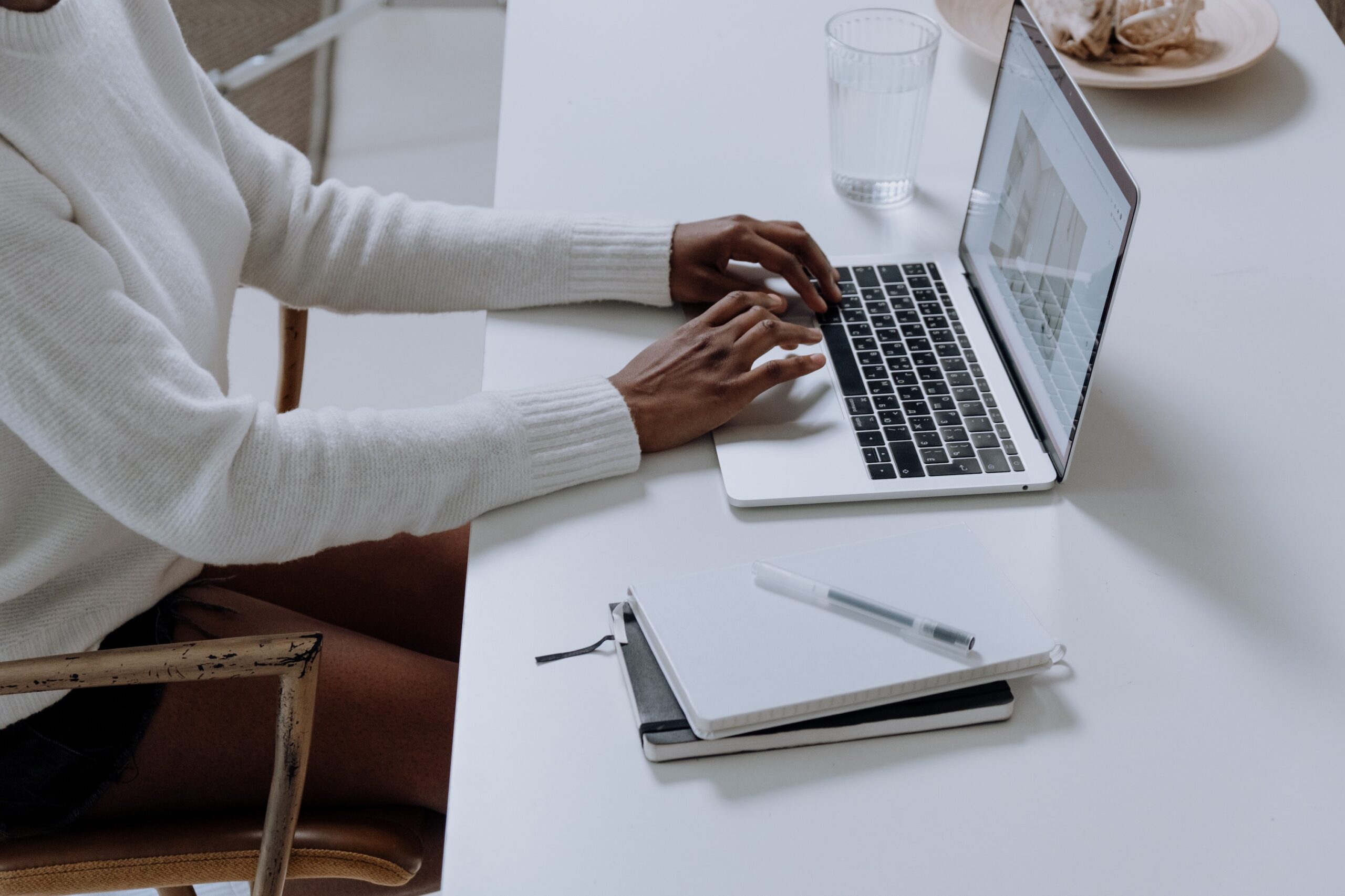 Image to portray eLearning training showing a person working at a laptop with a couple of notebooks and pen to the side of them