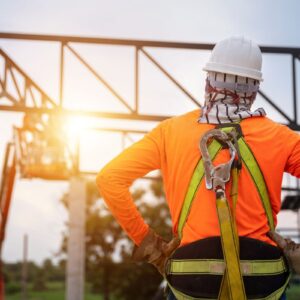Worker in high vis top, hard hat and harness looking at construction in front of them
