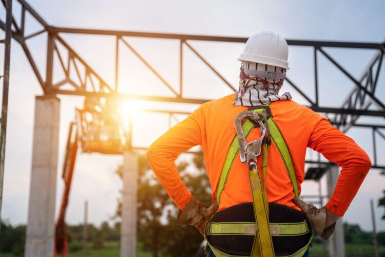Worker in high vis top, hard hat and harness looking at construction in front of them
